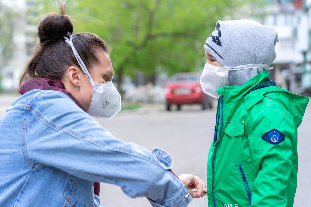 A woman and child wearing face masks for protection outdoors.