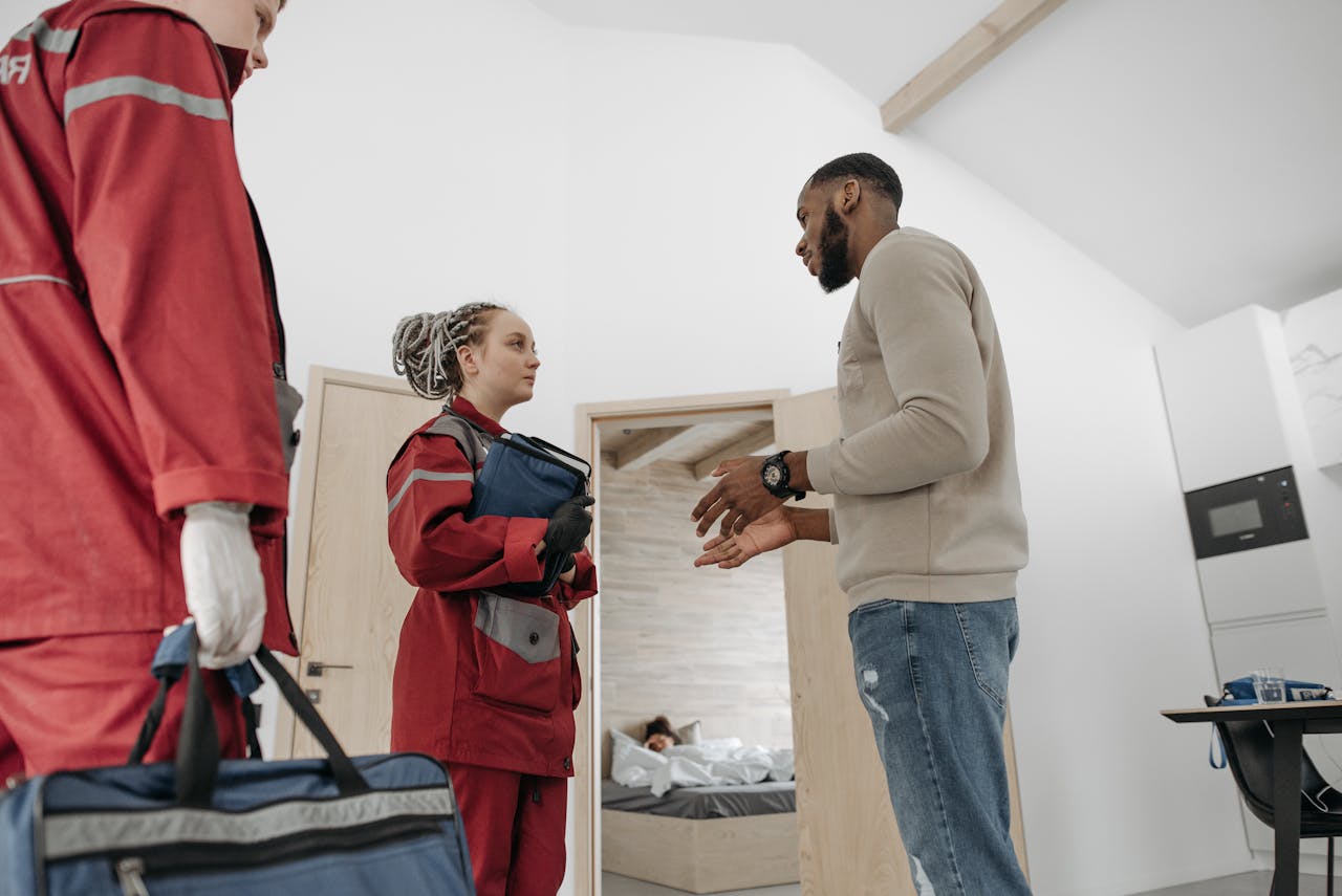The Art of Drawing Readers In: Your attractive post title goes here Paramedics in red uniforms assisting a person in a home setting, focusing on healthcare.